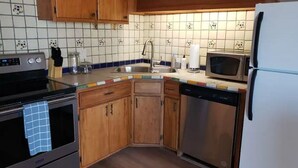 A compact kitchen with wooden cabinets, a stainless steel sink, a microwave, and a dishwasher.