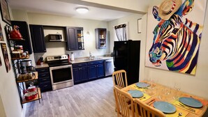 A compact kitchen with dark cabinets, a black refrigerator, and a dining area with wooden chairs and a table set for two. - Luxury Funky Fun 420, Walk Downtown wAC–Pets free! (Trinidad)