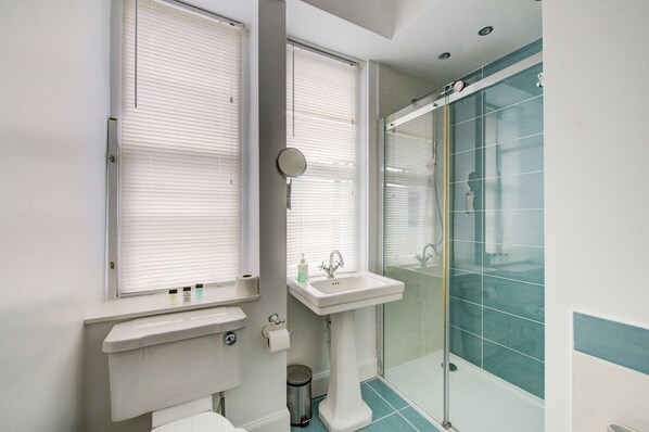 Une salle de bain avec deux lavabos, des toilettes et une douche à parois de verre.