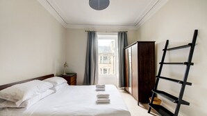 A hotel room with a bed, a wardrobe, a desk, and a window with curtains.
