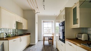 A kitchen with a dining table, chairs, a kettle, a toaster, and an oven.