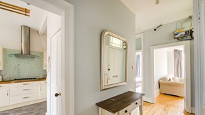 A modern kitchen with a gas stove, white cabinets, and a stainless steel range hood.