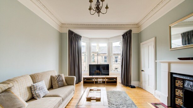 A living room with a sofa, coffee table, TV stand, and fireplace.