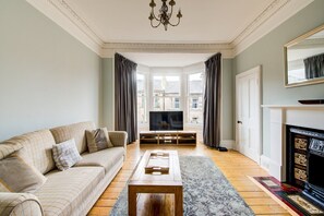 Un salon comprenant un canapé, une table basse, un meuble pour la télévision et une cheminée.