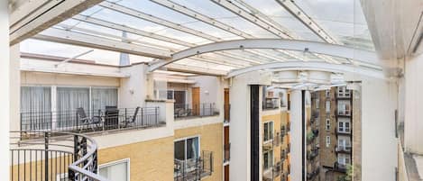 A multi-level residential building with a glass atrium, balconies, and a courtyard.
