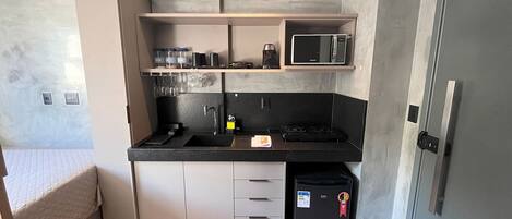 Una cocina compacta con microondas, estufa y refrigerador.