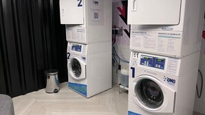 Two stacked washing machines in a room with a black curtain and a tiled floor. - Flat Gold Get One - João Pessoa (João Pessoa)