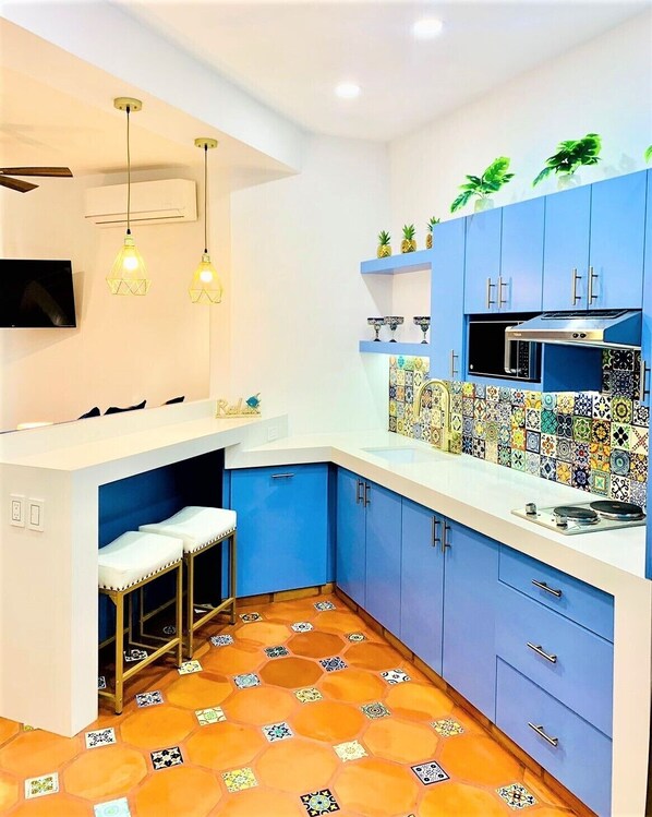 A modern kitchen with blue cabinets, a tiled backsplash, and a small bar area with stools.