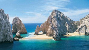 A coastal landscape with rocky formations and a sandy beach.