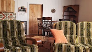 Ein gemütliches Wohnzimmer mit gestreiften Polstersesseln, einem Holzespeisetisch und einer Küche im Hintergrund.
