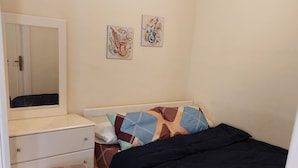 A bedroom with a bed, a dresser with drawers, a small stool, and two abstract paintings on the wall. - Cozy / Comfy Studio (Hurghada)
