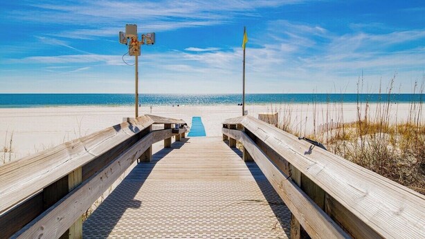 A wooden boardwalk leading to a beach with a clear sky. - Phoenix VII 203 | Orange Beach, AL (Orange Beach)