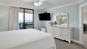 A bedroom with a bed, a dresser, a television, and a balcony with a view. - Phoenix VII 203 | Orange Beach, AL (Orange Beach)