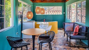 Un interior acogedor con techo de madera, una mesa redonda, sillas, un sofá y una pequeña zona de cocina.