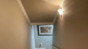 Eine Holztreppe mit Handlauf, die zu einer Zwischenebene mit einem gerahmten Bild an der Wand führt.