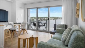 Een moderne woonkamer met een bank, eethoek en grote schuifdeuren die uitkomen op een balkon met uitzicht.