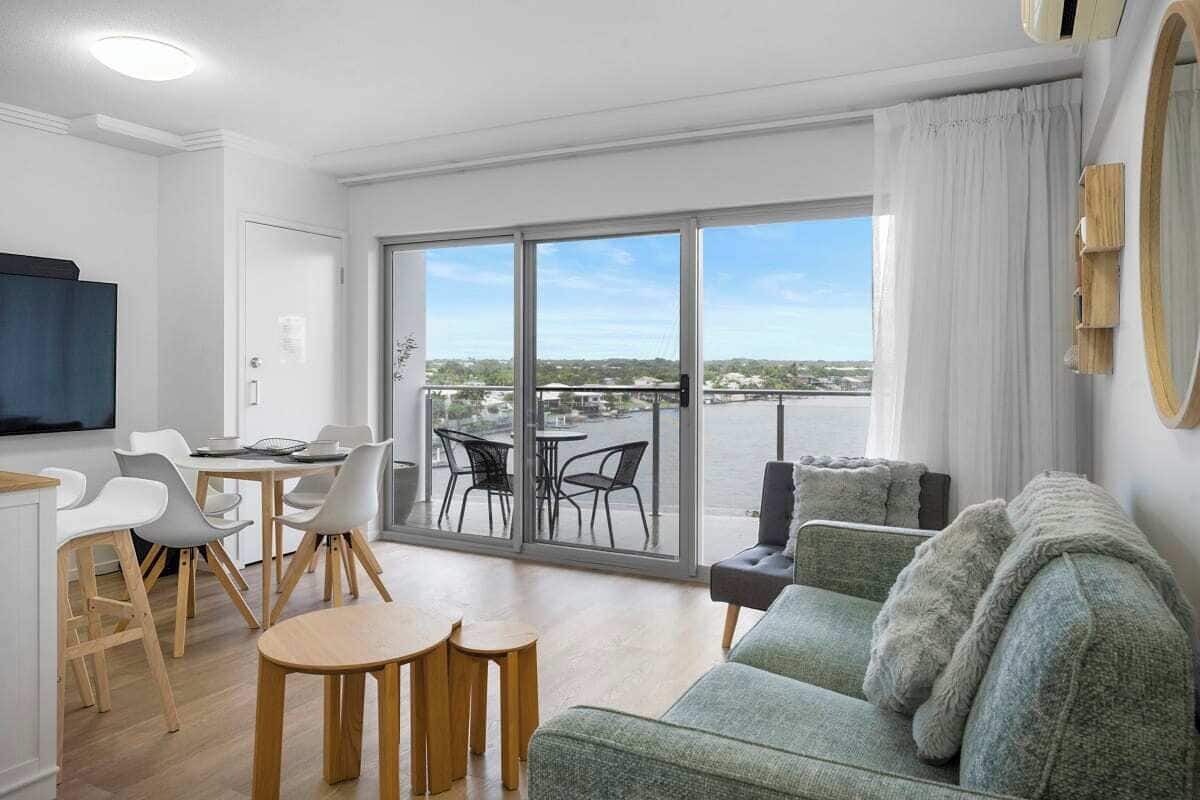 Un salon moderne comprenant un canapé, un coin repas et de grandes portes-fenêtres coulissantes donnant sur un balcon avec vue.
