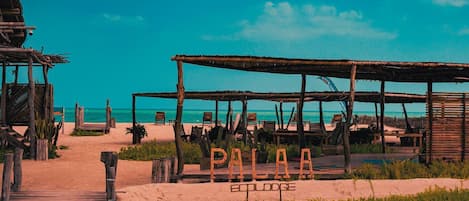A beach setting with wooden structures and seating areas, labeled "PALAA ECOLODE."
