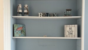 A room with a light blue wall and white shelves. There are decorative items on the shelves, including a seahorse, a 'RELAX' sign, and a 'NO Wake Zone' sign. - Seaside Sunsets, Our Oceanfront Home In Aripeka (Spring Hill)