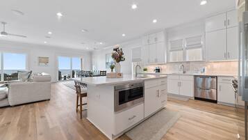 Una cocina moderna con armarios blancos, electrodomésticos de acero inoxidable y una isla central.