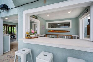 Un espace bar avec un comptoir, des tabourets et une décoration sur le thème du surf.
