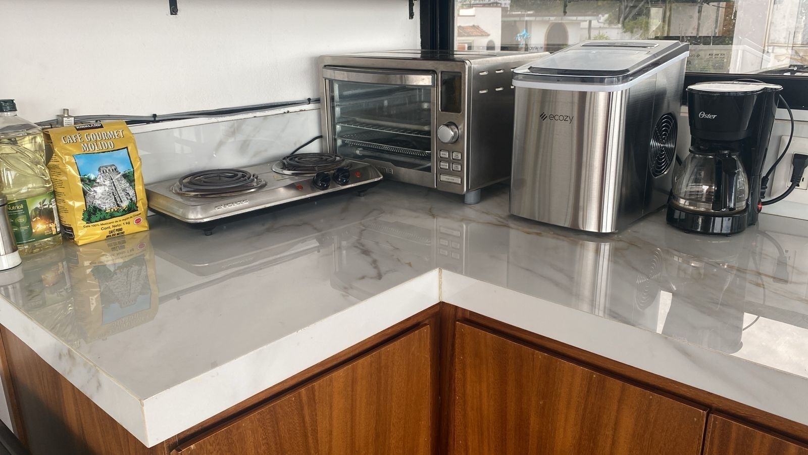 A kitchen with a stainless steel toaster oven, a coffee maker, and a bag of coffee pods on the counter.