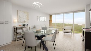 Ein moderner Essbereich mit einem Glastisch, weißen Stühlen und Blick ins Freie.