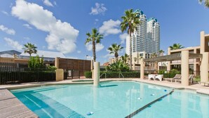 Ein Pool mit klarem, blauem Wasser, umgeben von Palmen und einem modernen Gebäude im Hintergrund.