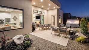 A modern house with a patio area featuring a dining table and chairs, a barbecue grill, and a hot tub. - Desert Dreaming 2 Bedroom, Den, Pet Friendly, Hot Tub EV Charger (Washington)