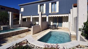 A modern house with a swimming pool, outdoor seating, and a stone pathway. - Villa with pool near the beach (Banjole)