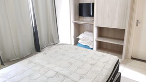 Un dormitorio con cama, televisor en un estante y armario.