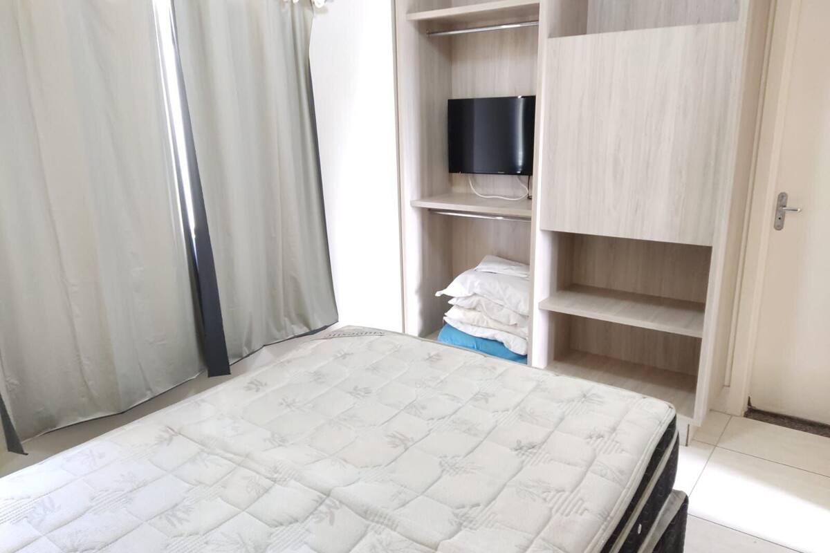 A bedroom with a bed, a TV on a shelf, and a wardrobe.