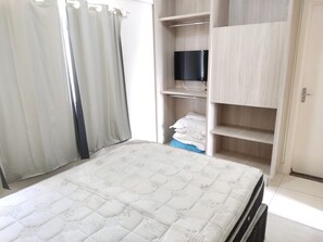Un dormitorio con cama, televisor en un estante y armario.