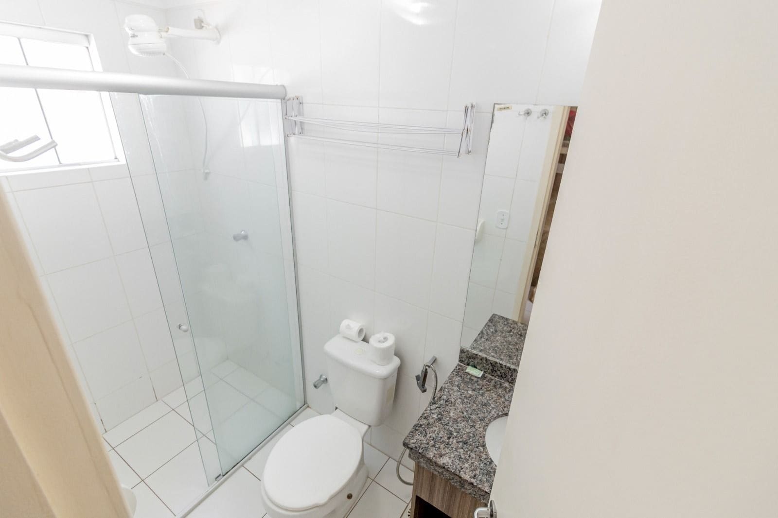 Un baño con cabina de ducha de vidrio, inodoro y encimera de granito.