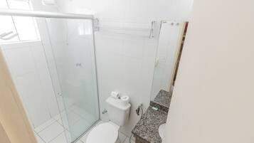 Un baño con cabina de ducha de vidrio, inodoro y encimera de granito.