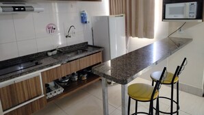 Cocina compacta con encimera de granito, estufa integrada, microondas y un pequeño comedor con dos sillas.