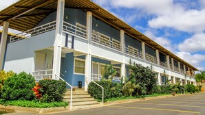 A two-story building with a balcony, a parking lot, and a clear sky. - LACQUA II (Caldas Novas)