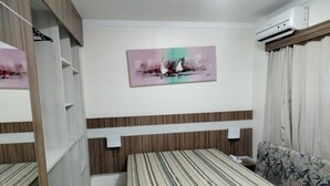 A bedroom with a bed, a sofa, a wardrobe, and a painting on the wall. - LACQUA II (Caldas Novas)