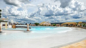 Ein Poolbereich mit einer Fontäne, Liegestühlen und einem Gebäude im Hintergrund.