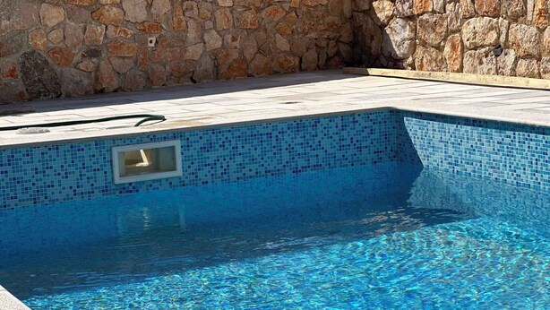 A swimming pool with clear blue water, surrounded by stone walls and a tiled deck. - Villa with large pool- wheelchair accessible (Dobrinj)