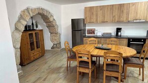 A kitchen with a stone archway, wooden cabinets, a round dining table with chairs, and a refrigerator. - Villa with large pool- wheelchair accessible (Dobrinj)