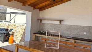 An outdoor kitchen with a wooden table, benches, and a hanging light fixture. - Villa with large pool- wheelchair accessible (Dobrinj)
