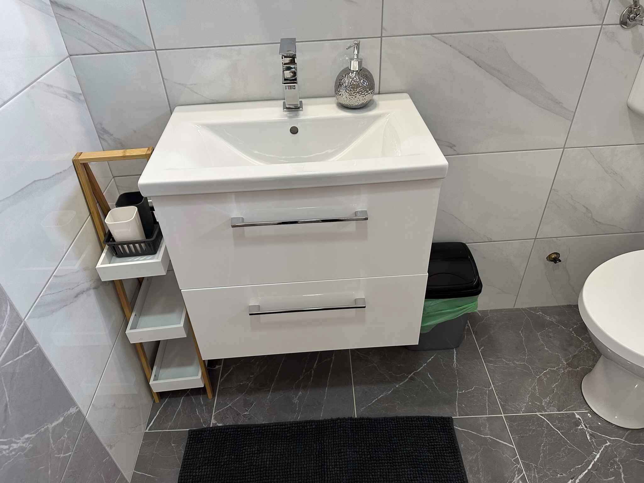 A bathroom with a white sink, a mirror, and a toilet.