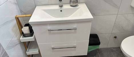 A bathroom with a white sink, a mirror, and a toilet.