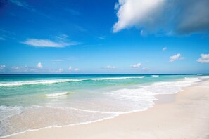 Uma praia com águas azul-claras e areal arenoso.
