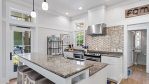 Una cocina moderna con una isla grande, electrodomésticos de acero inoxidable y un salpicadero con diseño de mosaico.