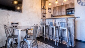 A modern kitchen with wooden cabinets, a built-in microwave, and a large clock on the wall. - Appartement du Rif - Welkeys (Huez)