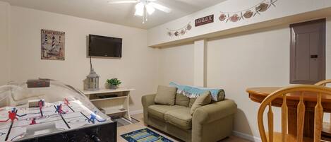 Una sala de estar con mesa de fútbol de mesa, televisor, sofá y una silla de madera.