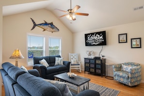 Relax in this spacious living room with a large window, comfortable sofa, and a flat-screen TV.