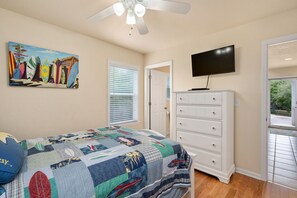A bedroom with a bed, a dresser, a television, and a painting on the wall. - Salada Sea Breeze: 5 min. walk to the beach, oceanside (Nags Head)